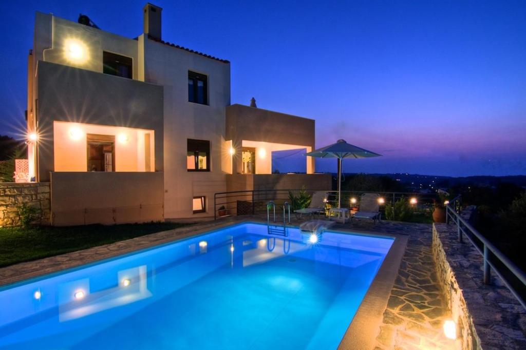 a swimming pool in front of a house at night at Villa Emilie in Agios Dimitrios