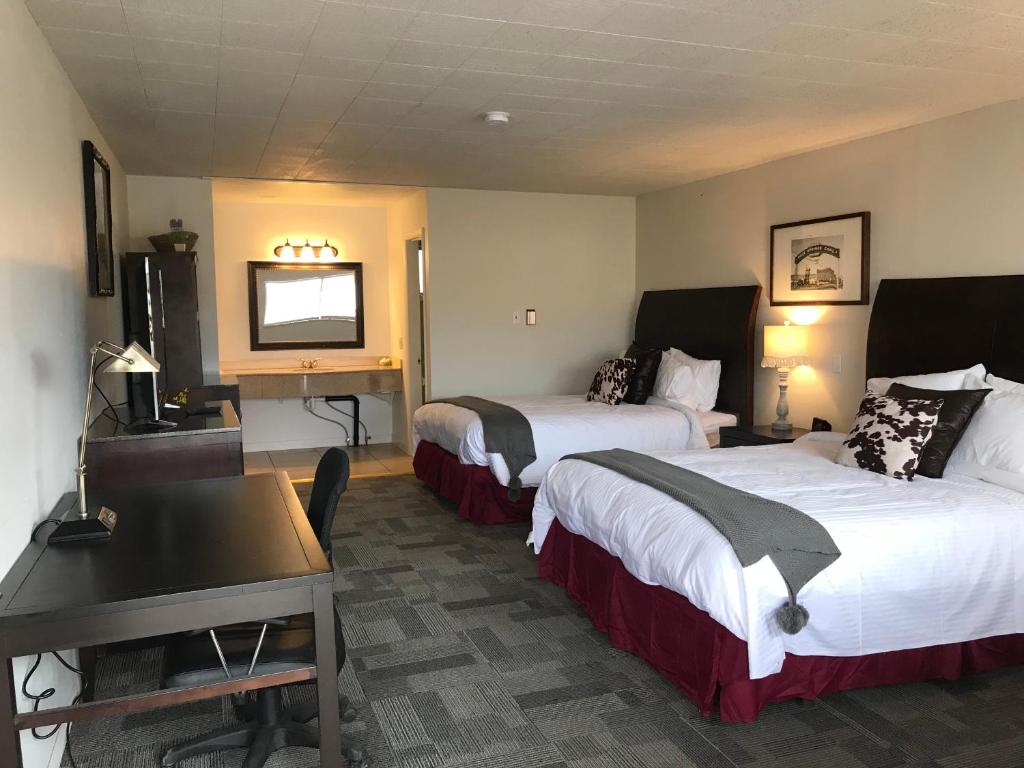 Habitación de hotel con 2 camas, escritorio y TV. en Country West Motel of Rock Springs en Rock Springs