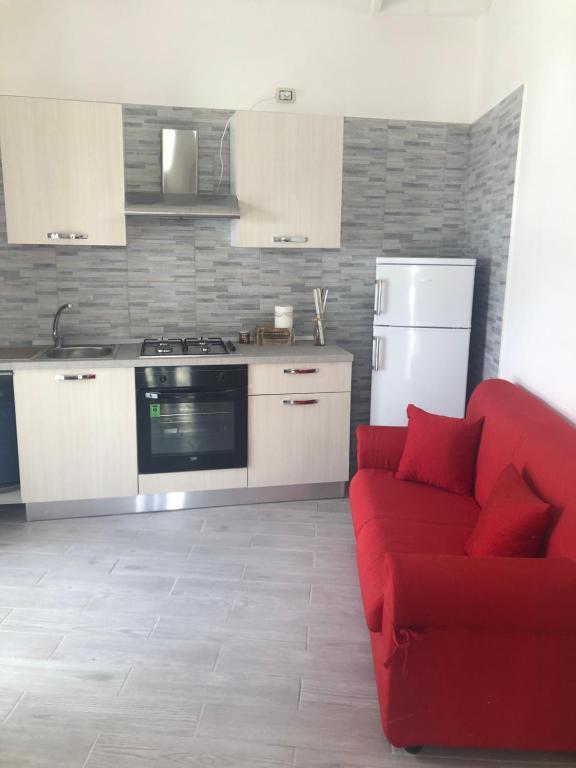 uma sala de estar com um sofá vermelho e uma cozinha em Piccolo fiore em Capaccio-Paestum