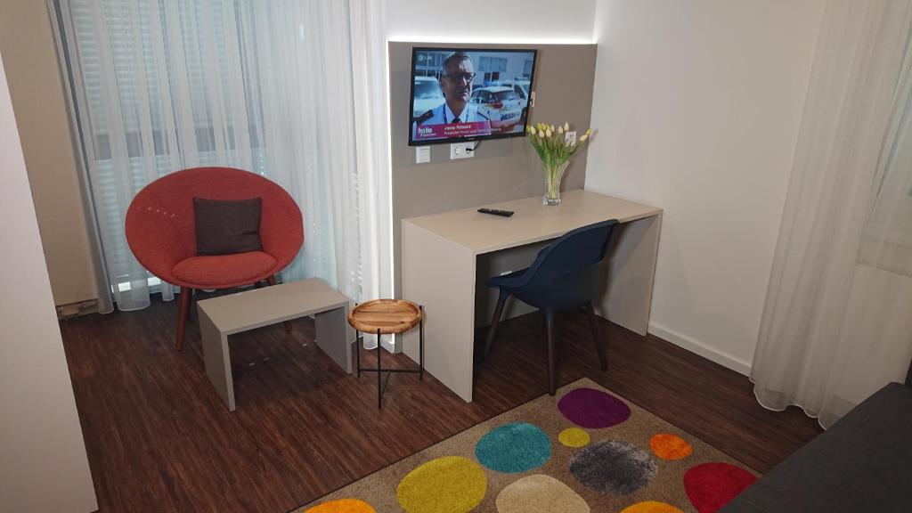 a room with a desk and two chairs and a television at Apart-House Nürnberg in Nuremberg