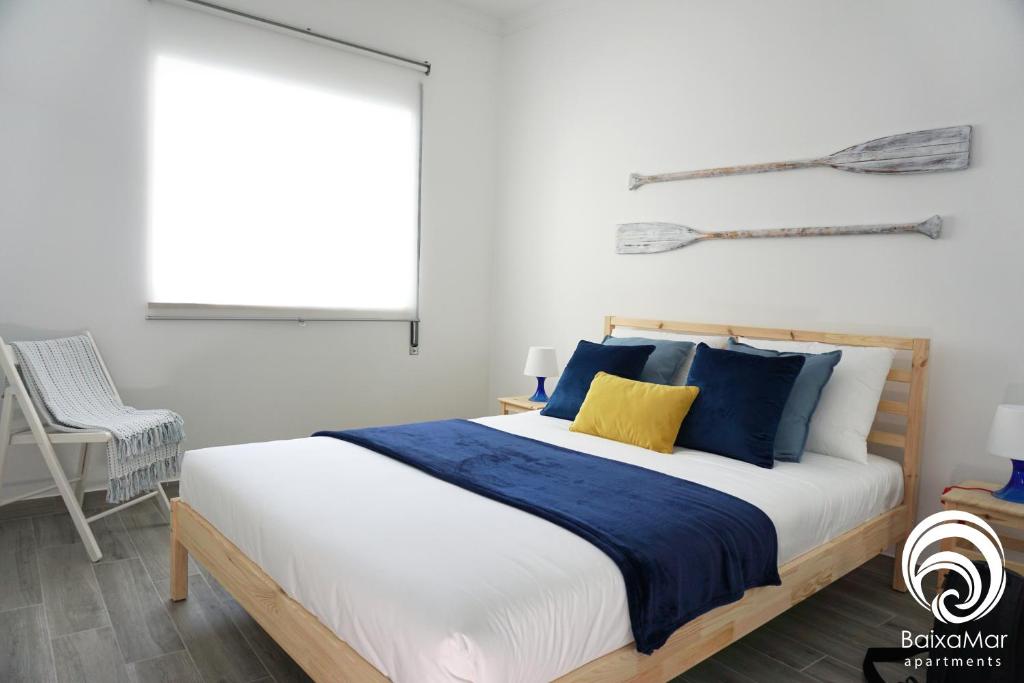 a bedroom with a bed with blue pillows and a window at BaixaMar Apartments in Olhão