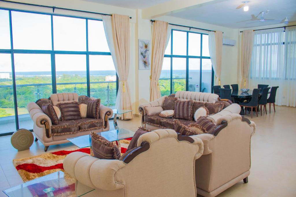 una sala de estar con sofás y un comedor con ventanas en Nyali Golf View Residence, en Mombasa