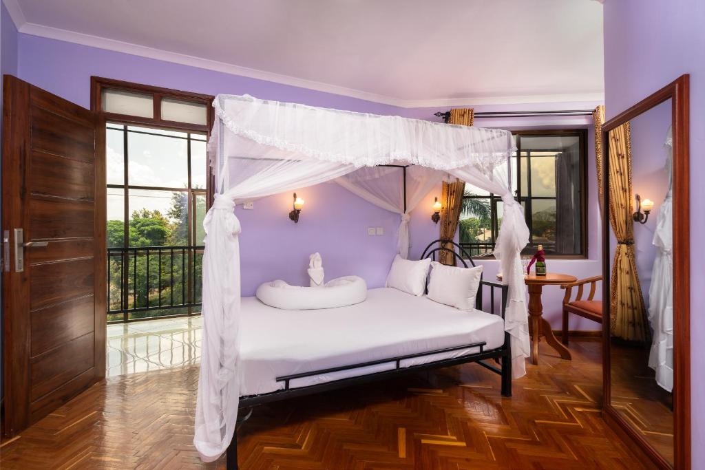 Mrimba Palm Hotel في أروشا: غرفة نوم بسرير مع مظلة