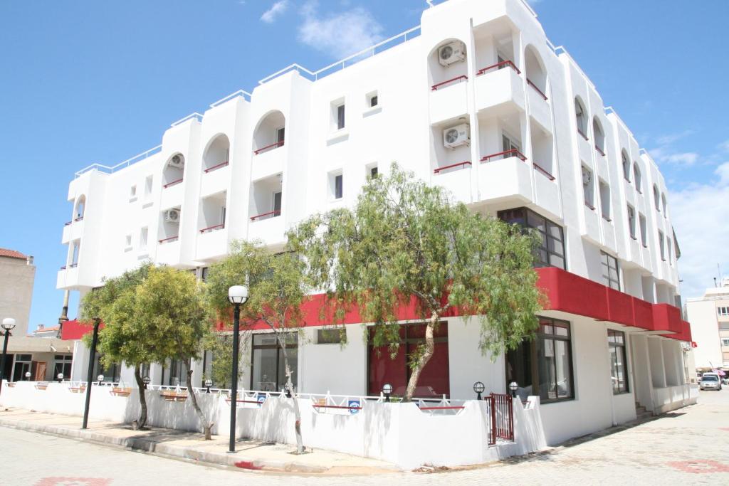 a white building with red trim on a street at Scala Nuova Annex in Cesme
