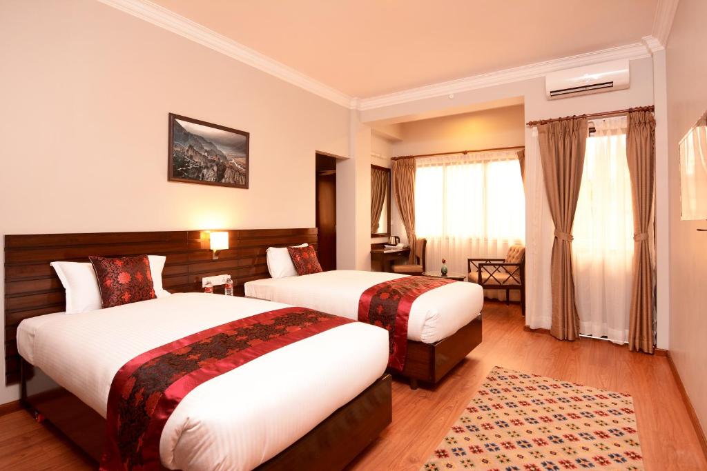 a hotel room with two beds and a window at Hotel Mudita in Kathmandu