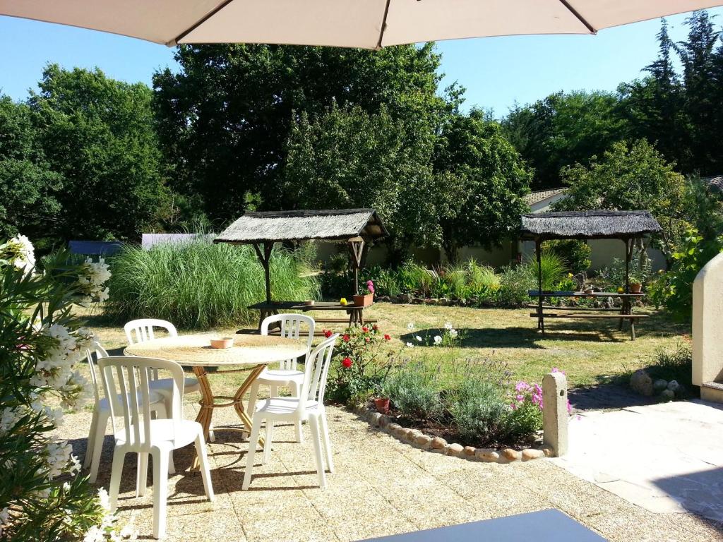 a patio with a table and chairs and an umbrella at Acacias Hôtel Motel in Vendays-Montalivet