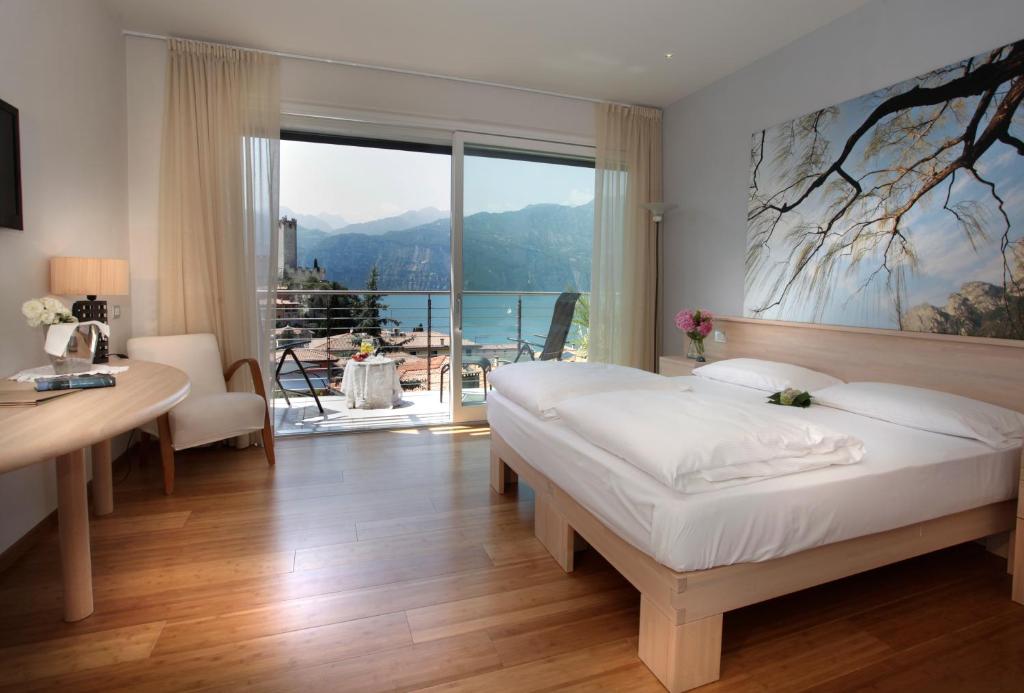 sypialnia z łóżkiem, biurkiem i oknem w obiekcie Eco Hotel Ariston w mieście Malcesine