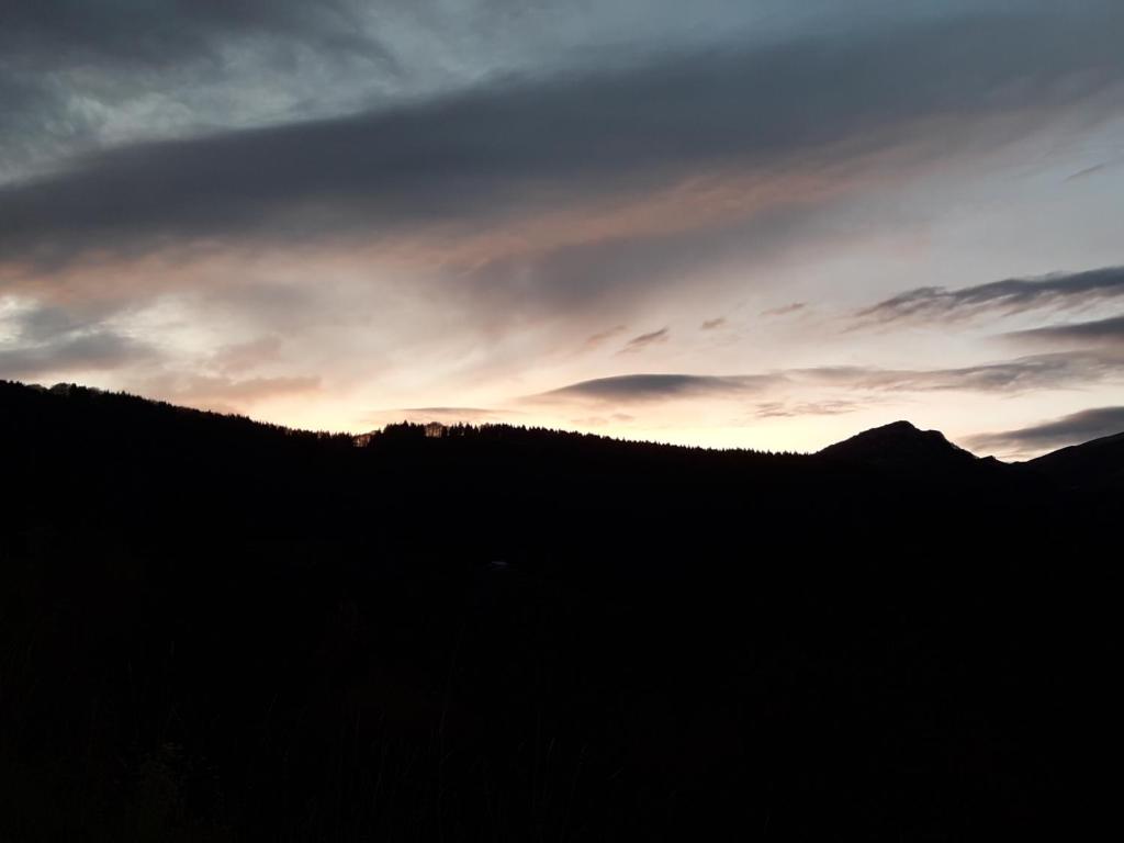 una silueta de una colina con una puesta de sol en el fondo en Residenza il bosco en Prada