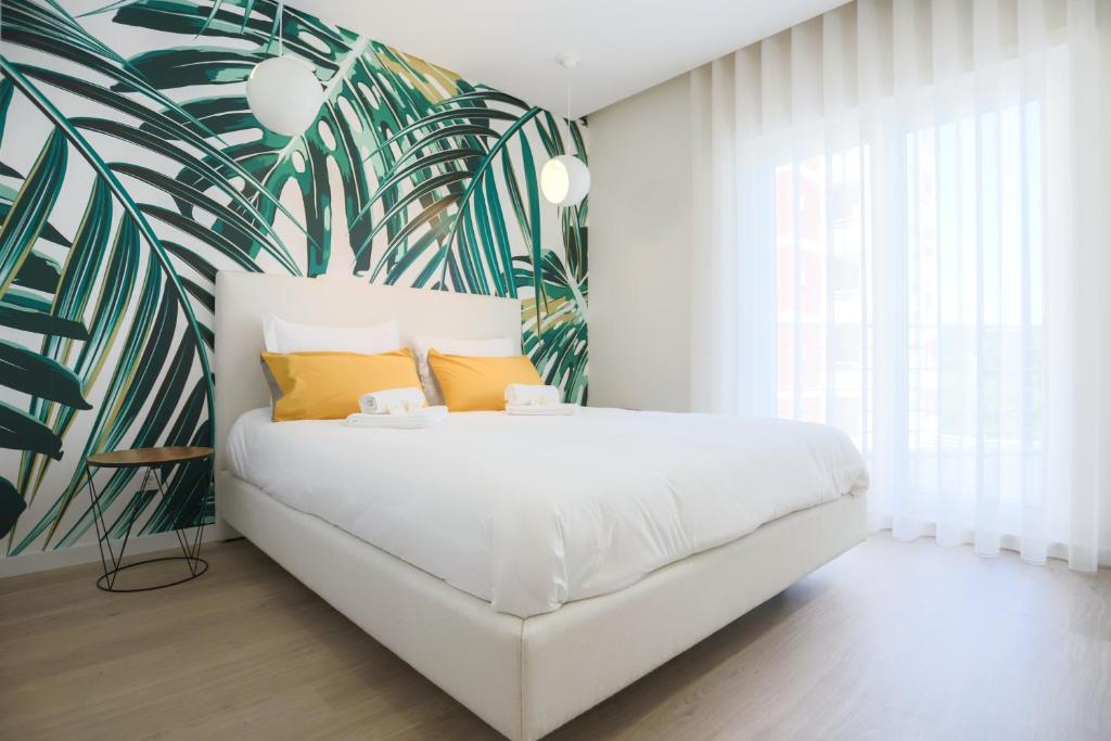 a bedroom with a white bed with a tropical mural at Pajaro Residence in Figueira da Foz