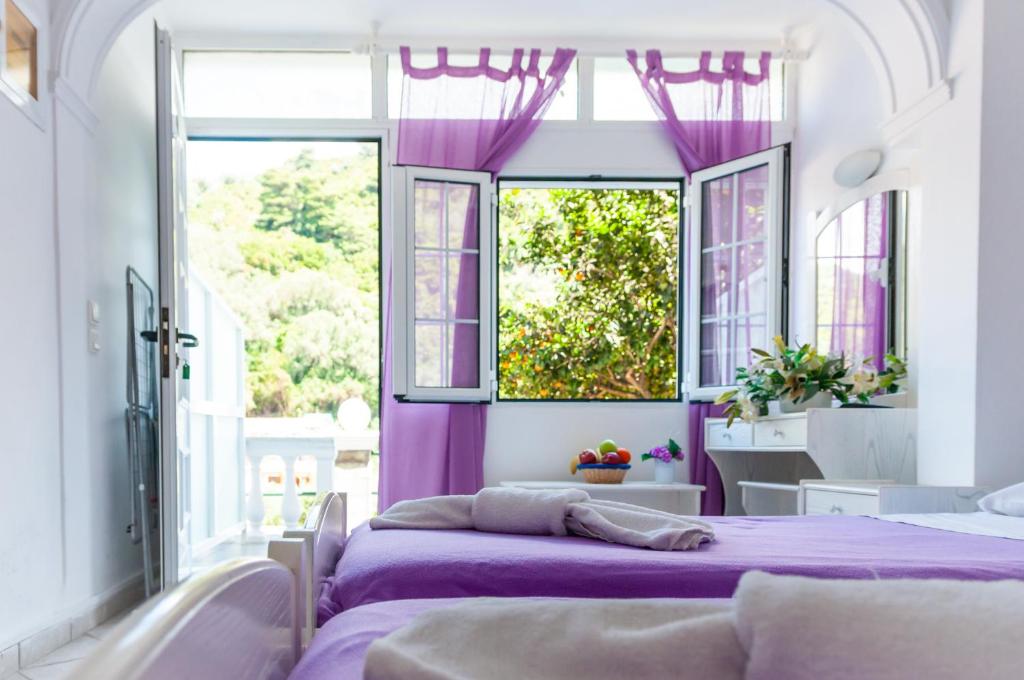 two beds in a room with purple curtains at Apart Hotel Blumarin in Agios Gordios