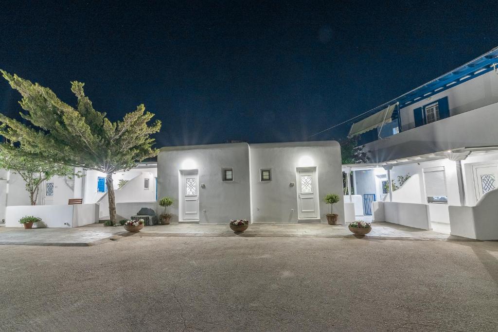 un edificio blanco con puertas blancas y una palmera en Flora's Houses Mykonos en Klouvas