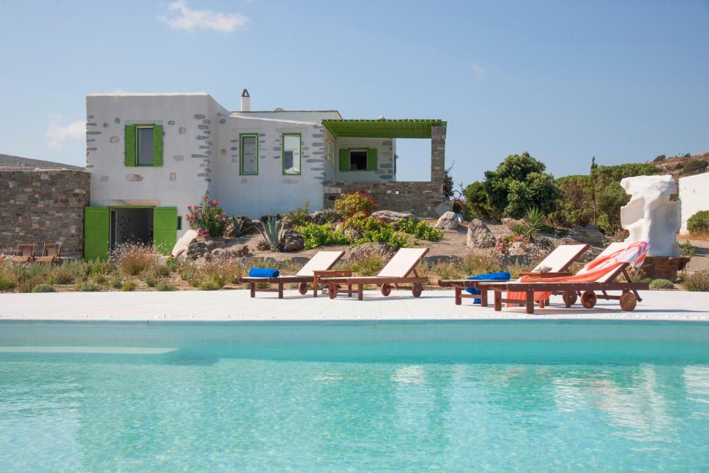 a pool with chairs and a house in the background at Villa Aeolos with 2 private pools in Sarakíniko