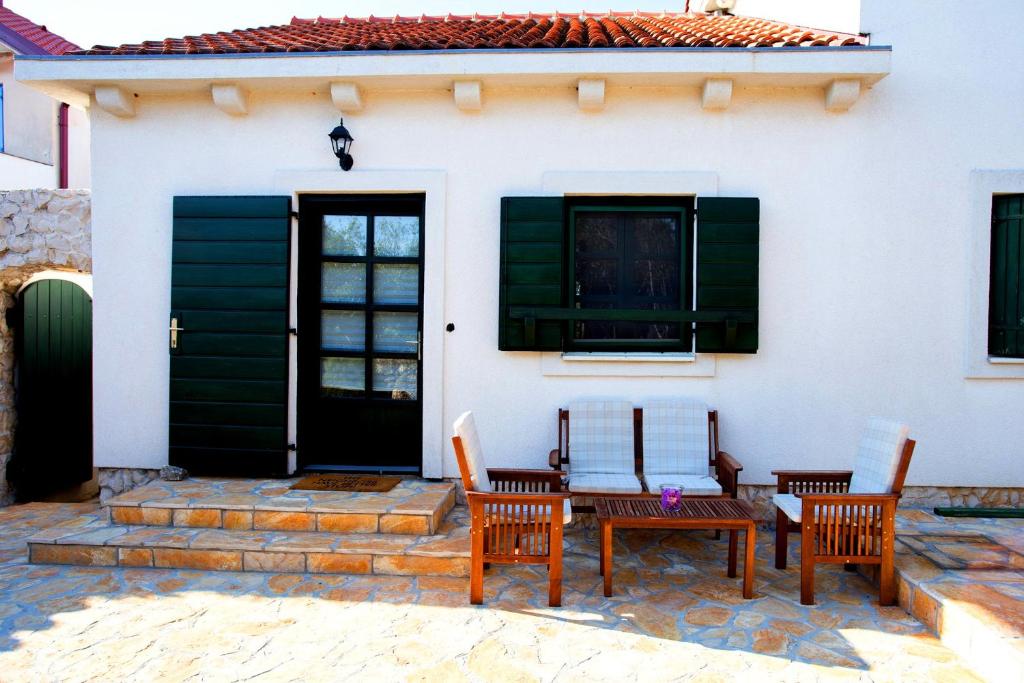 a patio with two chairs and a table in front of a house at Studio apartman - MELLITUS in Molat