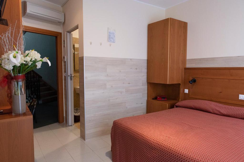 a bedroom with a red bed and a vase of flowers at Hotel Real in Sottomarina