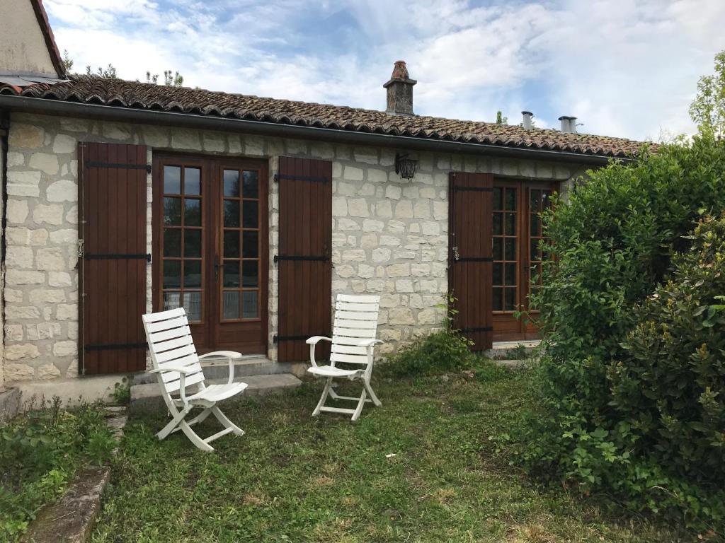 two white chairs sitting in front of a house at May's Cottage in Availles-Limouzine