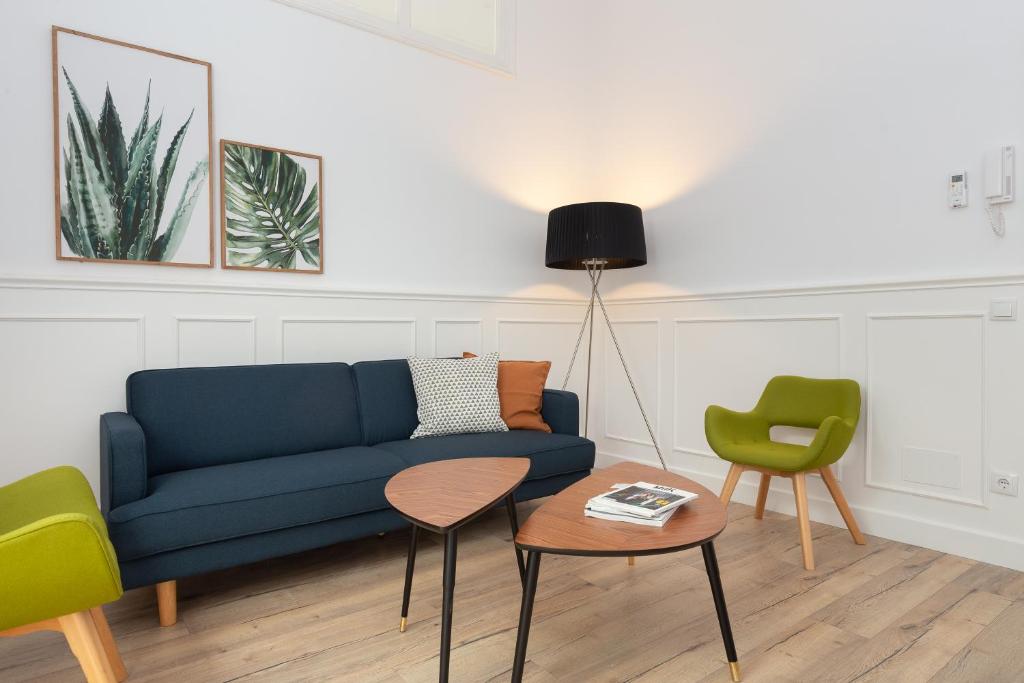 Casa Cosi - Eixample 1 في برشلونة: غرفة معيشة مع أريكة زرقاء وكرسيين أخضر