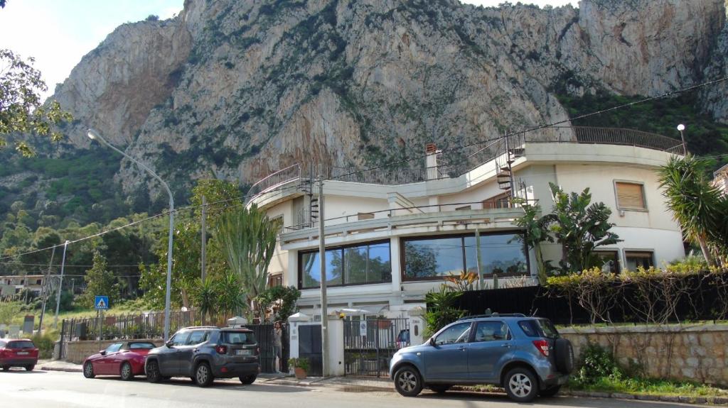 un edificio con auto parcheggiate di fronte a una montagna di Residenza Don Camillo a Mondello
