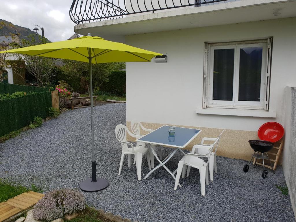 a table and chairs and an umbrella on a gravel patio at appartement Isabelle in Lau-Balagnas