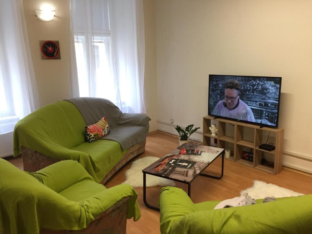 uma sala de estar com 2 sofás verdes e uma televisão de ecrã plano em Apartamento City em Košice