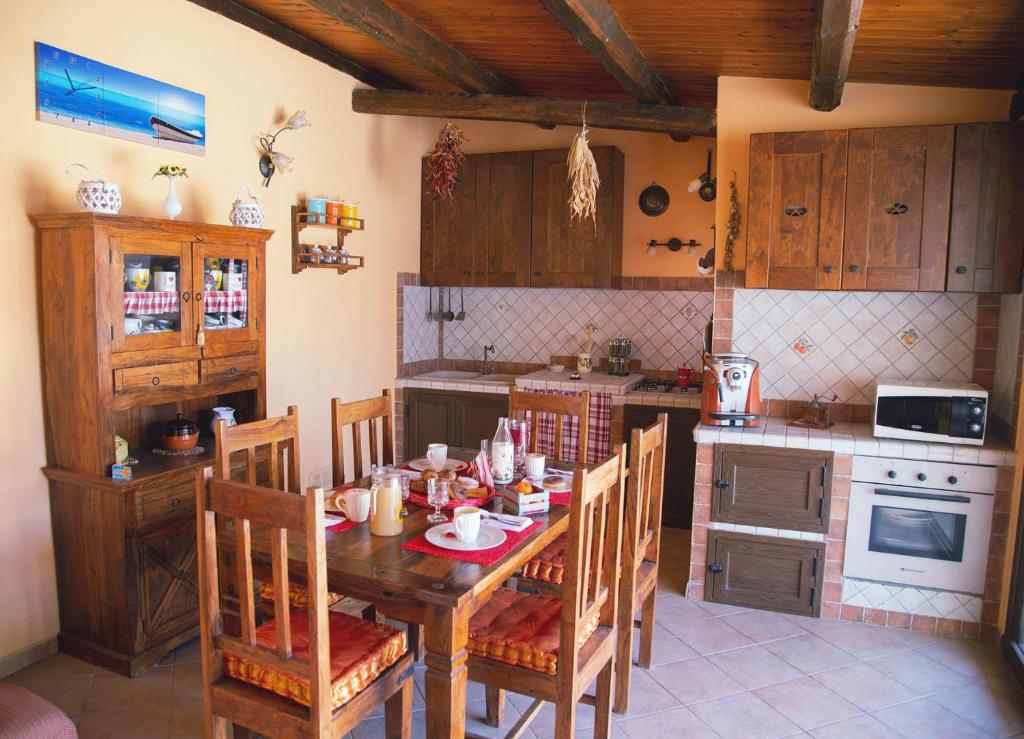 una cucina con tavolo e sedie in legno e una cucina con piano cottura di Il Girasole a Balestrate