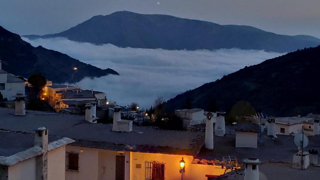 uma vista de uma cidade à noite com uma montanha em hostal ruta de las nieves em Capileira