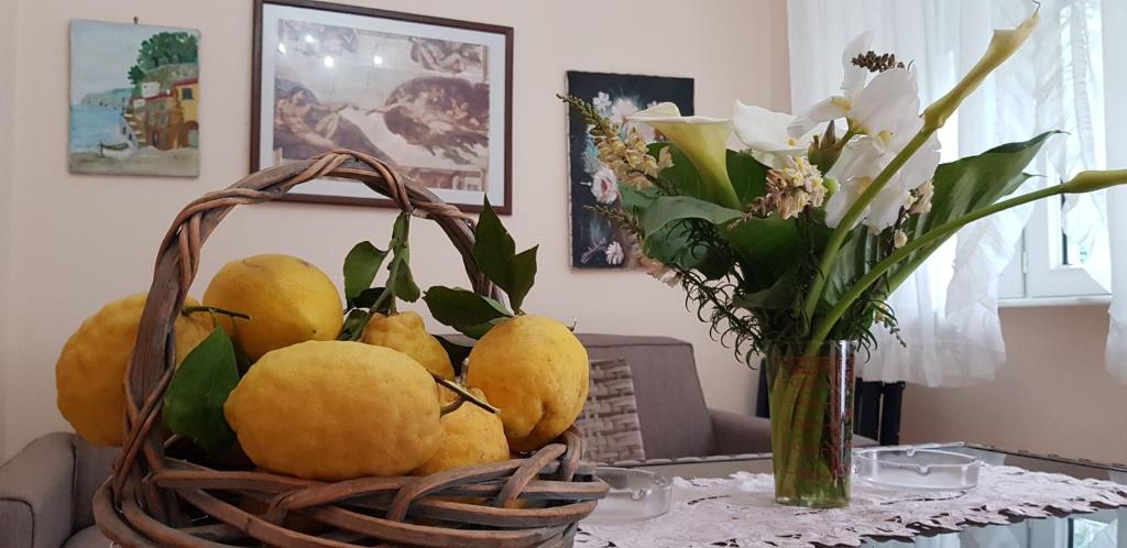 une corbeille de fruits sur une table avec un vase de fleurs dans l'établissement Casa Vacanza Giovanna, à Vietri