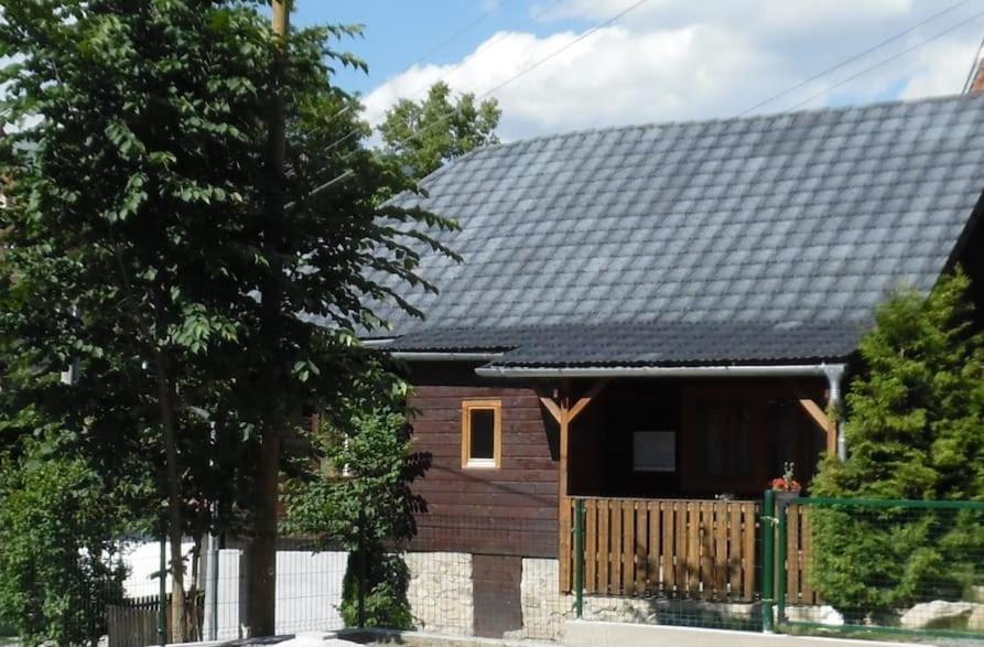 een huis met een zwart dak en een hek bij Drevenica u Porubäna in Jakubovany