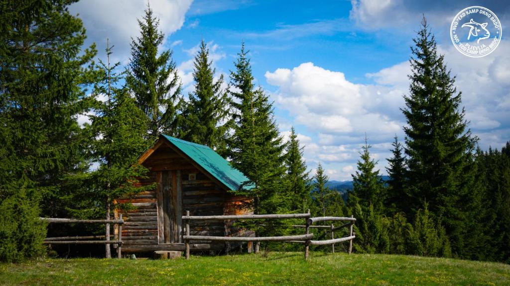 domek z bali z niebieskim dachem na polu w obiekcie Eco Camp Drno Brdo w mieście Kosanica