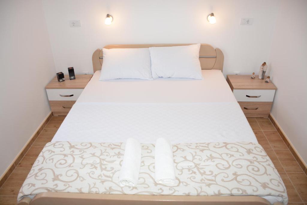 um quarto com uma cama branca com duas mesas de cabeceira em Apartmani Gaga em Tivat