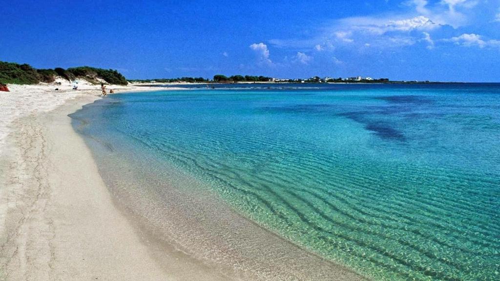 a beach with turquoise water and people walking on it at MAMA BED in Porto Cesareo