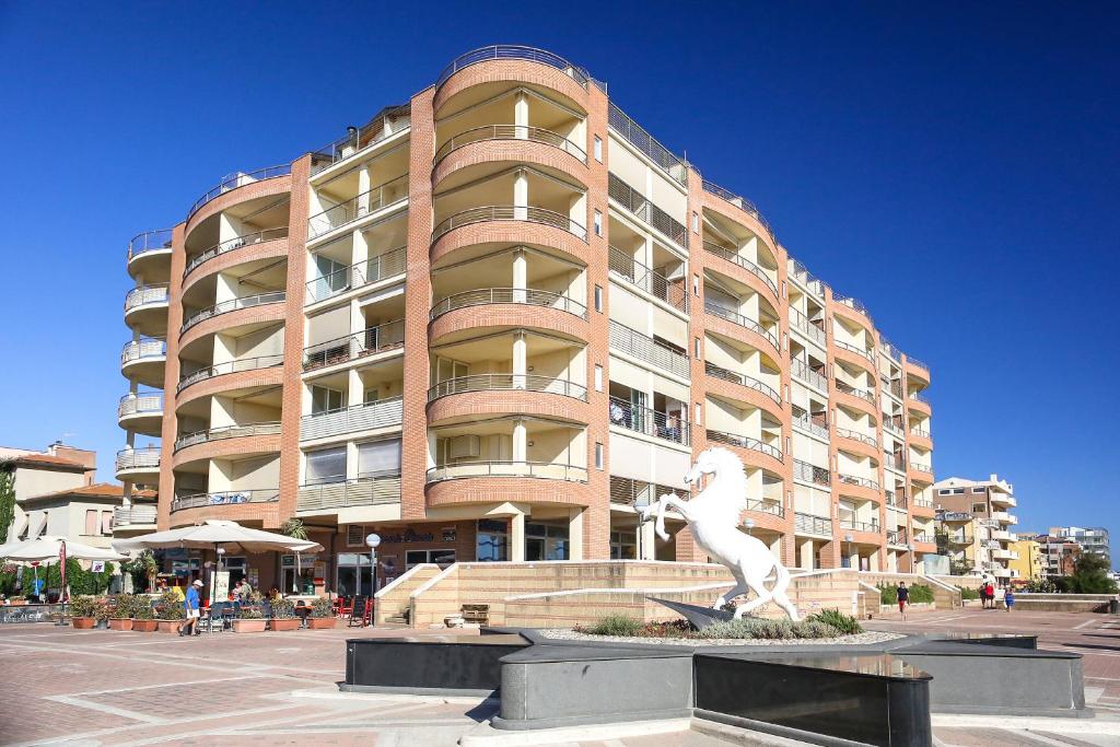 馬里納－迪格羅塞托的住宿－地中海公寓酒店，一座大建筑,前面有雕像