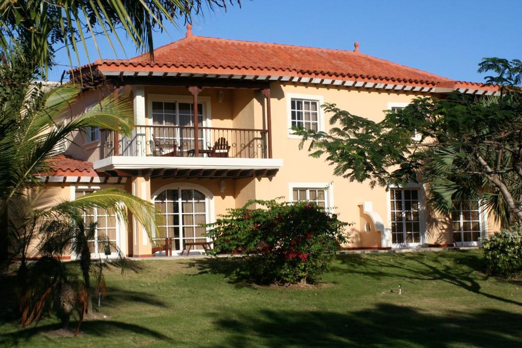 une grande maison jaune avec un toit rouge dans l'établissement The Golf Suites, à Punta Cana