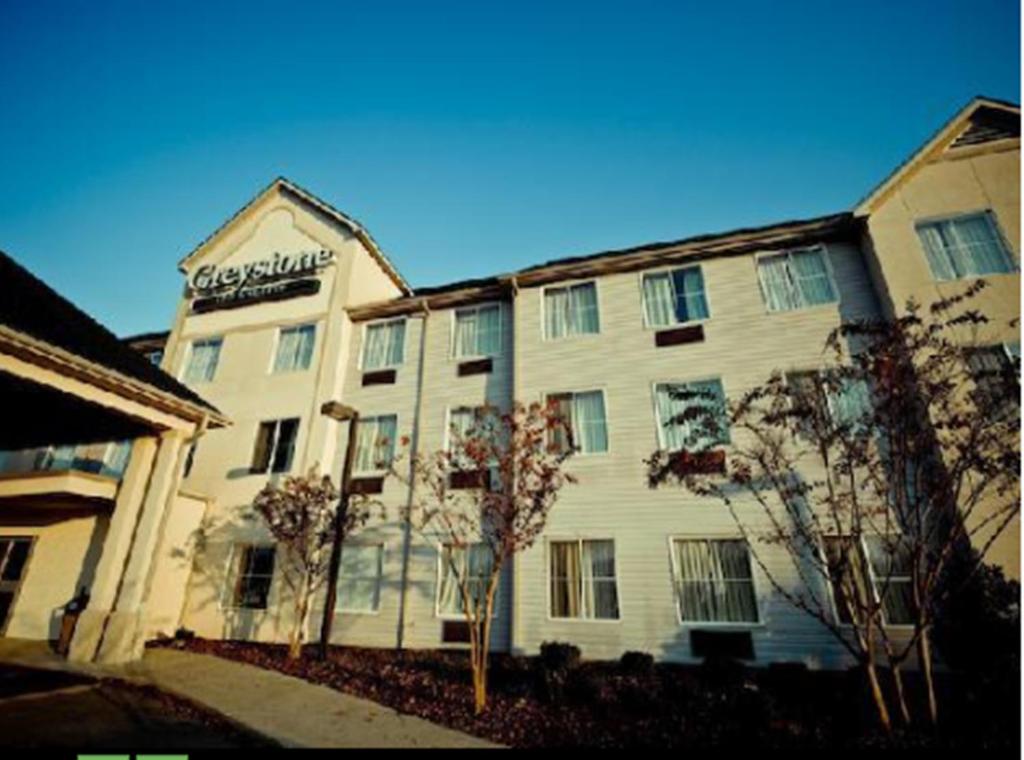 a large white building with a sign on it at Greystone Inn & Suites in Vance