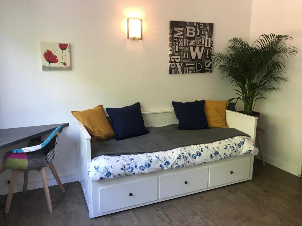 a bedroom with a white bed with blue and yellow pillows at T1bis meublé tout confort in Tours