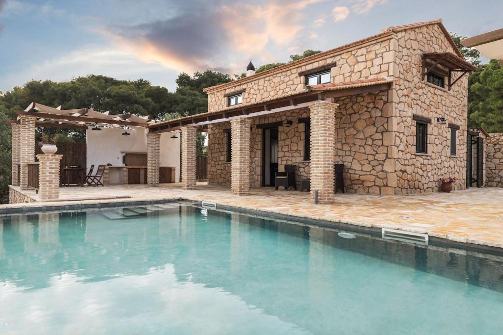 una casa in pietra con una piscina di fronte di Villa Margarita a Anafonítria