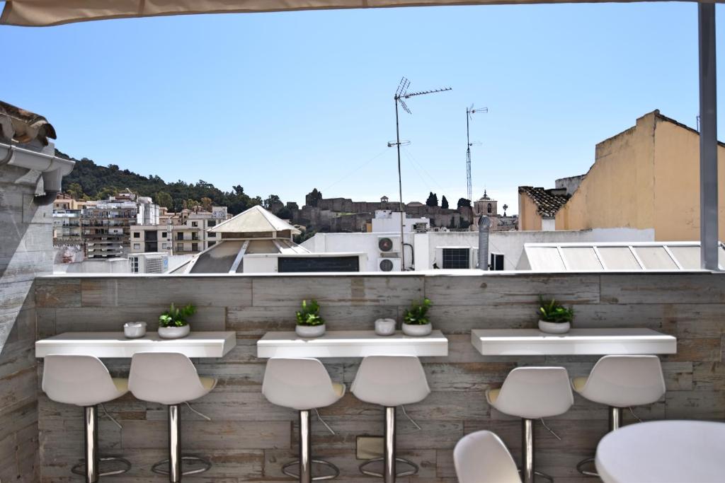 una fila de taburetes blancos sentados en un bar en la azotea en Apartamentos Marques De La Merced, en Málaga