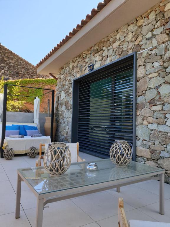 una mesa de cristal frente a una pared de piedra en Mas de la Petite Jeanne en Grimaud