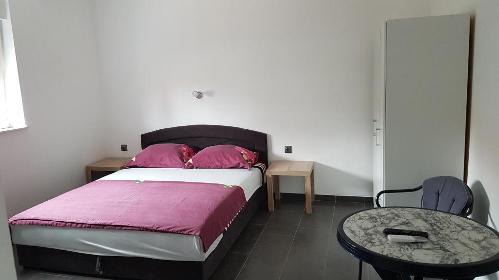 um quarto com uma cama com almofadas cor-de-rosa e uma mesa em Apartments STAR with Pool em Biograd na Moru