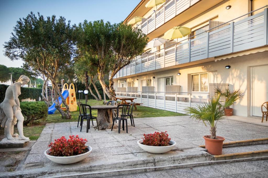 eine Terrasse mit einem Tisch, Stühlen und Pflanzen in der Unterkunft Yachting residence in Lignano Sabbiadoro