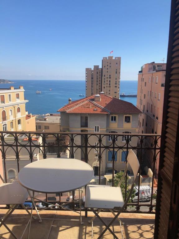 una mesa y sillas en un balcón con vistas al océano en villa juturne en Beausoleil