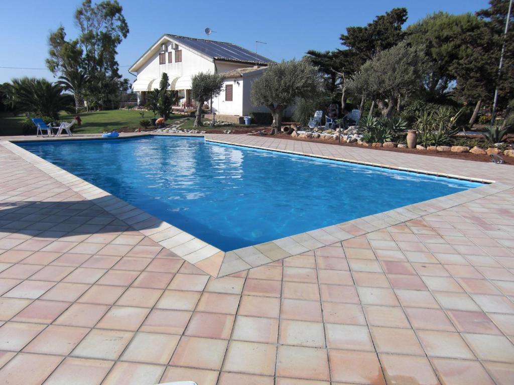 a swimming pool with a tile floor and a house at Il Dunnè in Vittoria