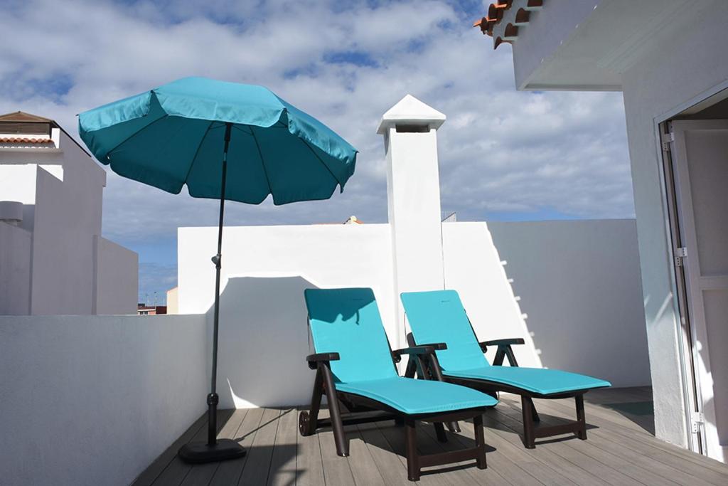 two blue chairs and an umbrella on a deck at Casa Serena in Puerto de la Cruz