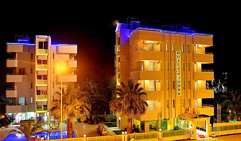 a tall yellow building with blue lights on it at Rumana Hotel in Anamur