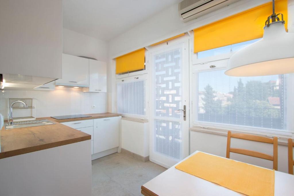 cocina con armarios blancos y ventana grande en Apartment Cankar, en Pula