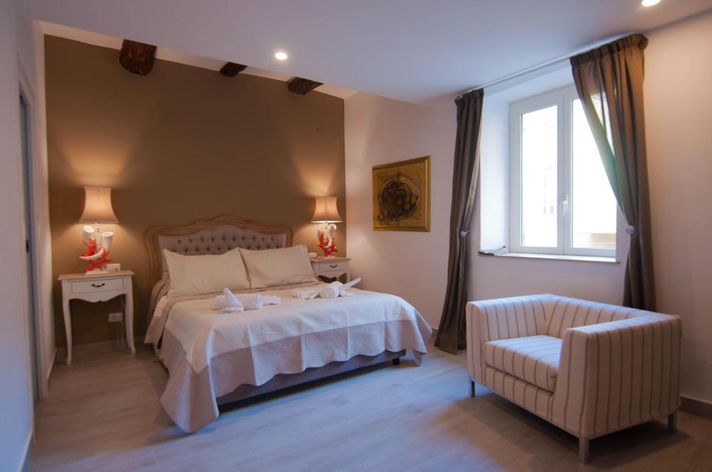 um quarto com uma cama, uma cadeira e uma janela em Relais Bijoux Napoli em Nápoles