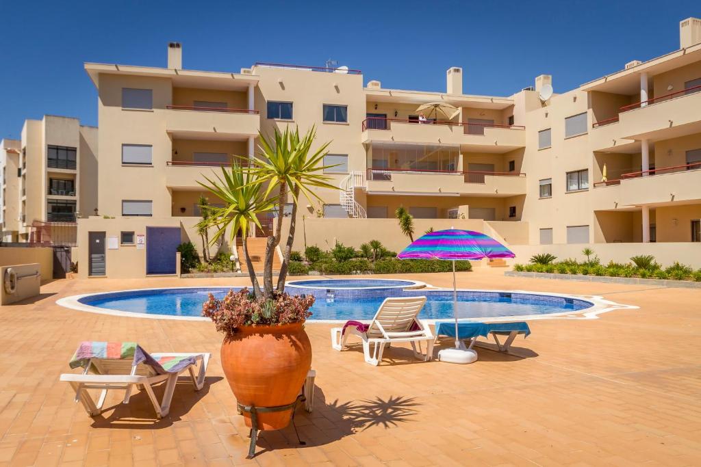 - une cour avec une piscine, des chaises et un parasol dans l'établissement The Hoffy Beach Apartment, à Lagos