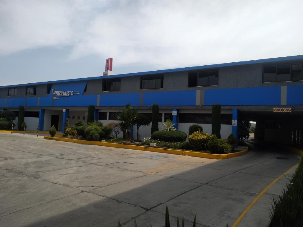 un bâtiment bleu et blanc avec un parking dans l'établissement Hotel Aeropuerto, à Toluca