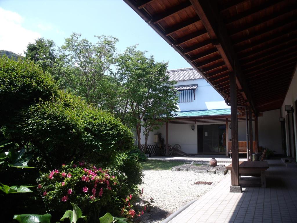 un porche de una casa con arbustos y flores en 御宿しんしま, en Matsuzaki