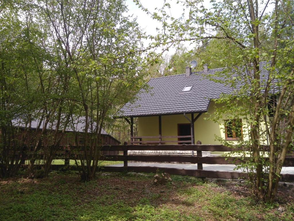 una pequeña casa amarilla con una valla de madera en Leśniczówka Leśny azyl en Stanisławice