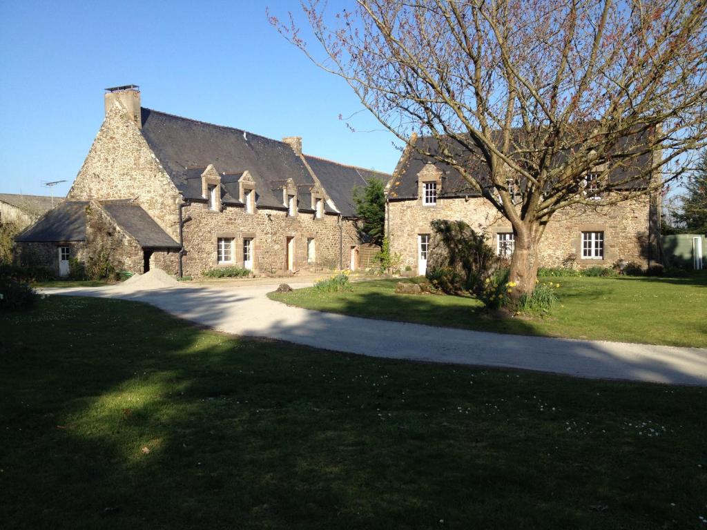 une grande maison en pierre avec un arbre en face de celle-ci dans l'établissement Maison d'hôtes "Bienlivien", à Saint-Coulomb